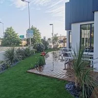 Aménagement paysagé d'une boulangerie avec terrasse bois et gazon synthétique - Mérignac #Gironde